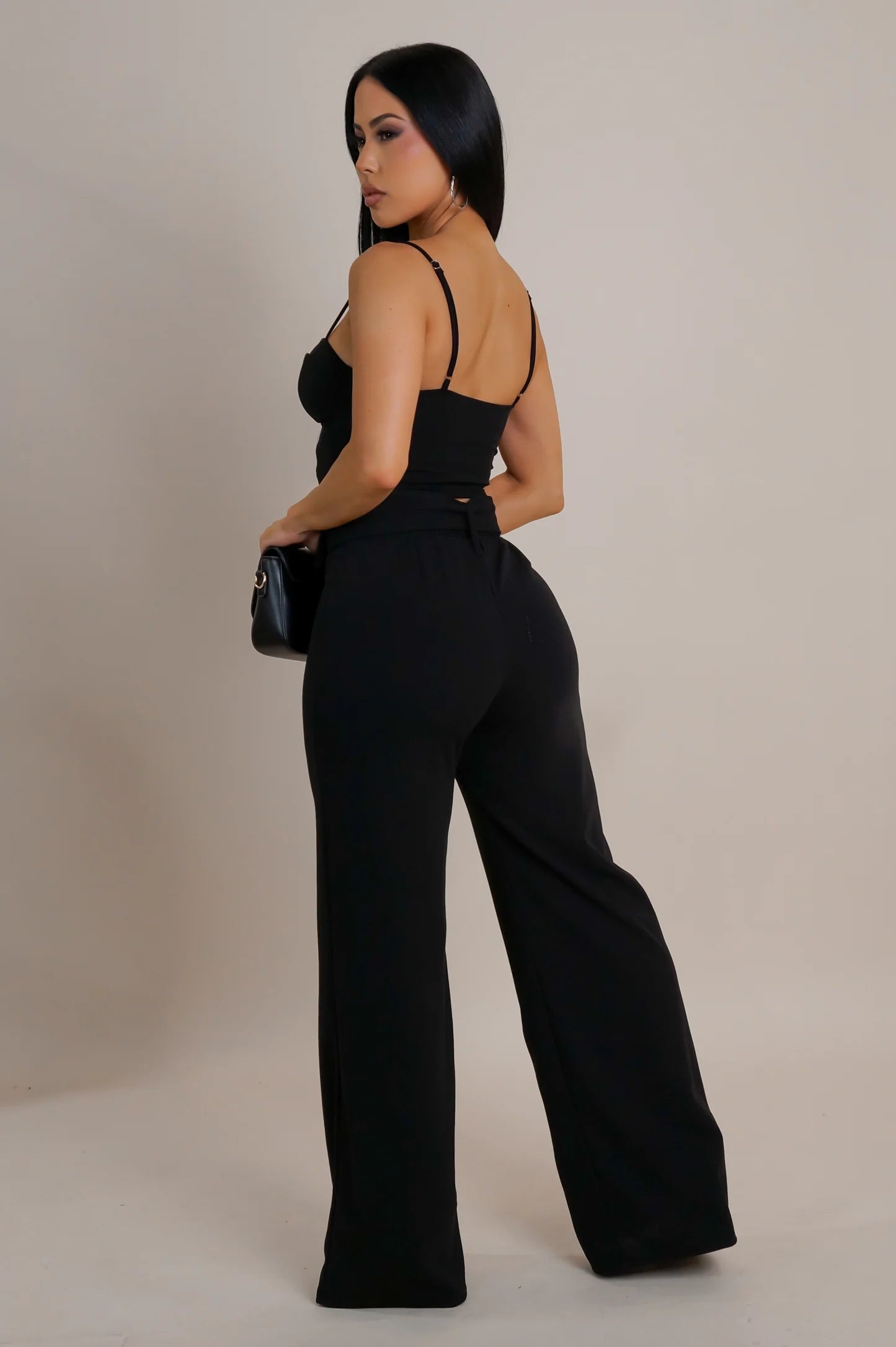 Model wearing black lace-up corset crop top with high-waisted wide-leg pants and rhinestone buckle belt